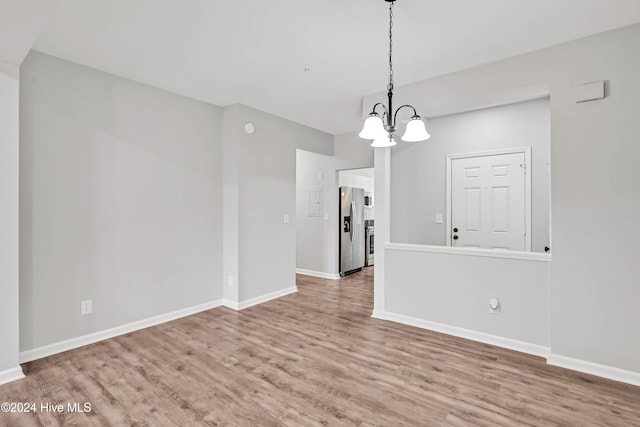 unfurnished dining area with a chandelier and light hardwood / wood-style floors