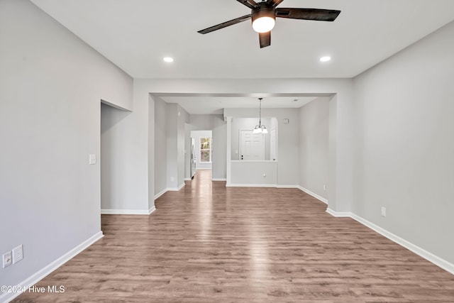 empty room with hardwood / wood-style floors and ceiling fan with notable chandelier