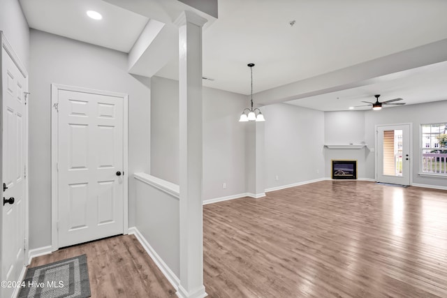 unfurnished living room featuring light hardwood / wood-style flooring and ceiling fan with notable chandelier