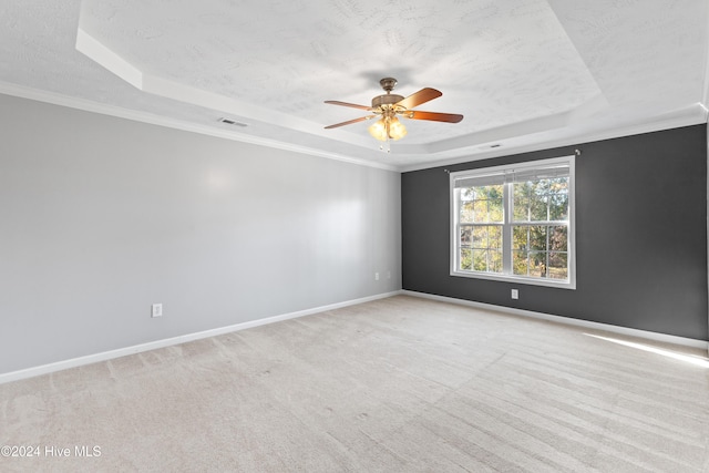 spare room with a tray ceiling, crown molding, ceiling fan, and light colored carpet