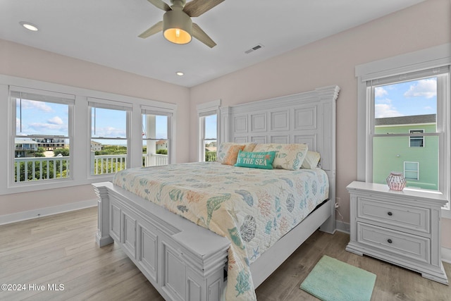 bedroom with light wood-type flooring, multiple windows, and ceiling fan