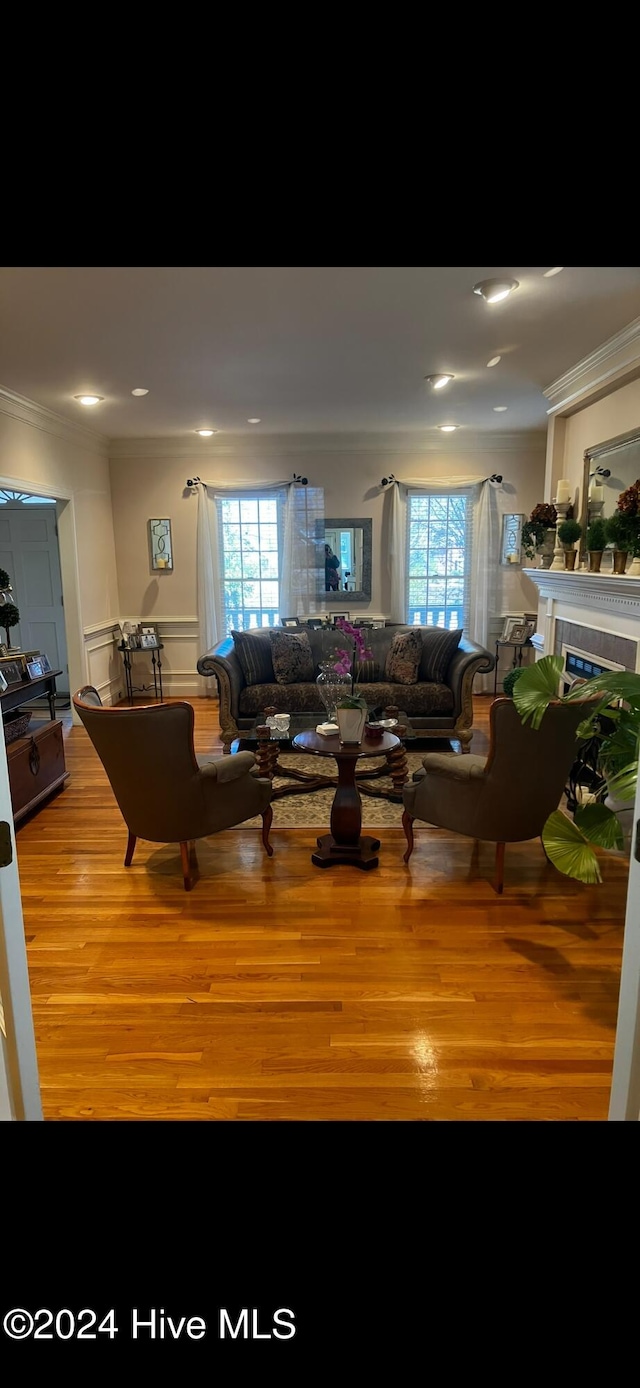 living room featuring light wood-type flooring, crown molding, and plenty of natural light