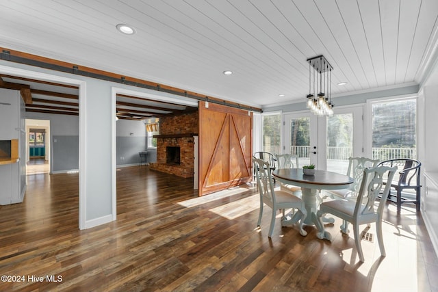 dining room with wooden ceiling, dark wood-type flooring, a brick fireplace, a barn door, and ornamental molding