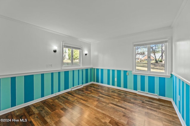 unfurnished room featuring a wealth of natural light, ornamental molding, and hardwood / wood-style flooring