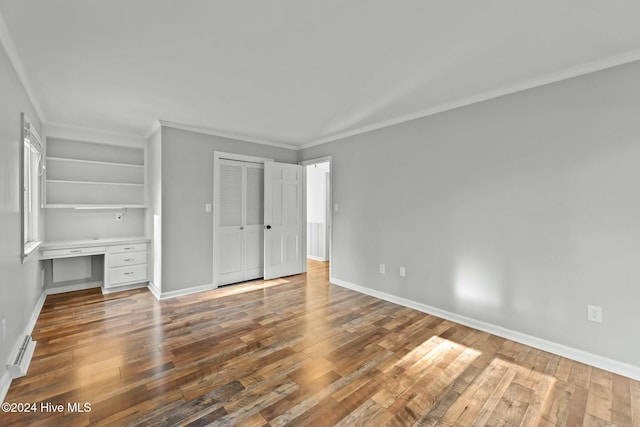 unfurnished bedroom with wood-type flooring, built in desk, and ornamental molding