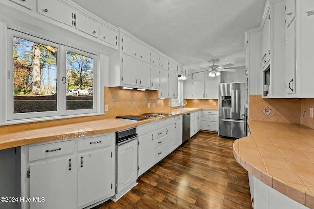 kitchen with ceiling fan, tile counters, stainless steel appliances, dark hardwood / wood-style floors, and white cabinets