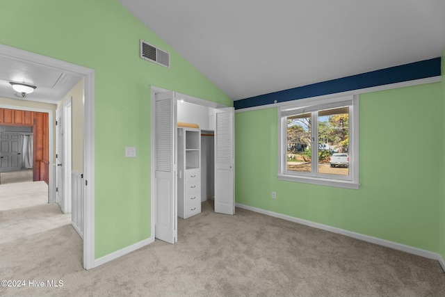 unfurnished bedroom with light carpet, vaulted ceiling, and a closet