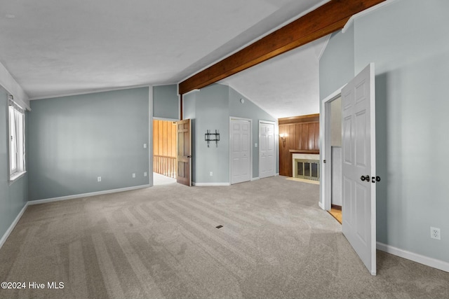 unfurnished living room featuring lofted ceiling with beams and light colored carpet