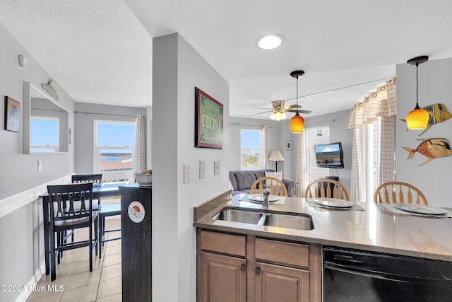 kitchen with dishwasher, sink, ceiling fan, light tile patterned floors, and a textured ceiling