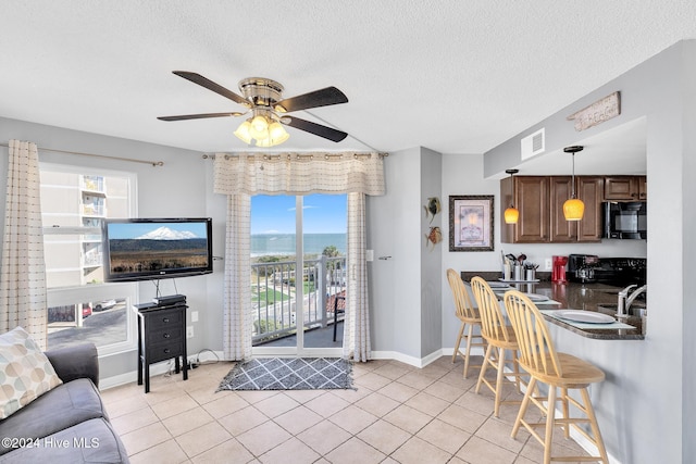 interior space featuring ceiling fan, light tile patterned floors, and a textured ceiling