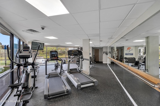 exercise room featuring a paneled ceiling and a wealth of natural light