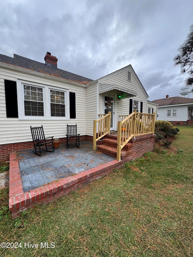 back of property with a patio area and a yard