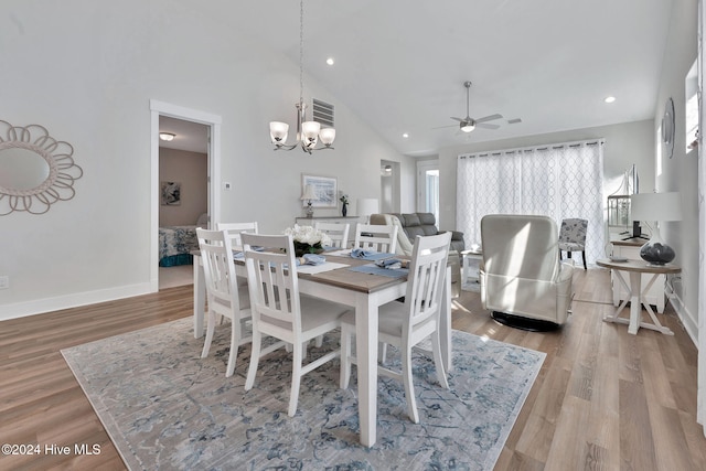 dining space featuring ceiling fan with notable chandelier, high vaulted ceiling, and light hardwood / wood-style flooring