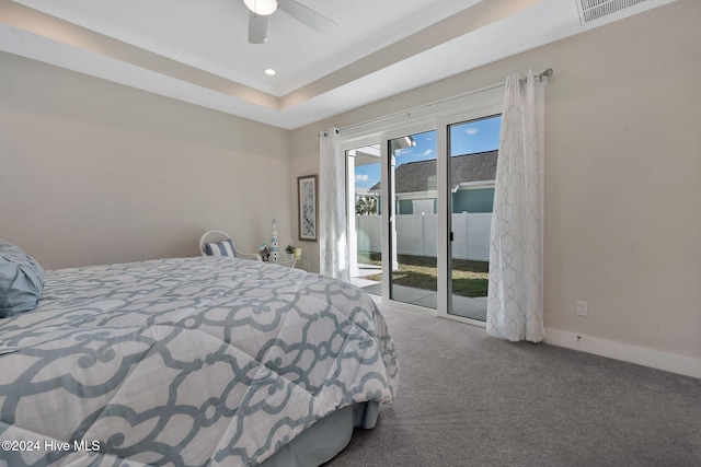 bedroom with a tray ceiling, access to exterior, ceiling fan, and carpet