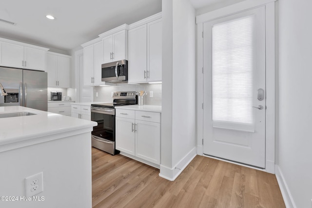 kitchen with light hardwood / wood-style flooring, white cabinets, and stainless steel appliances