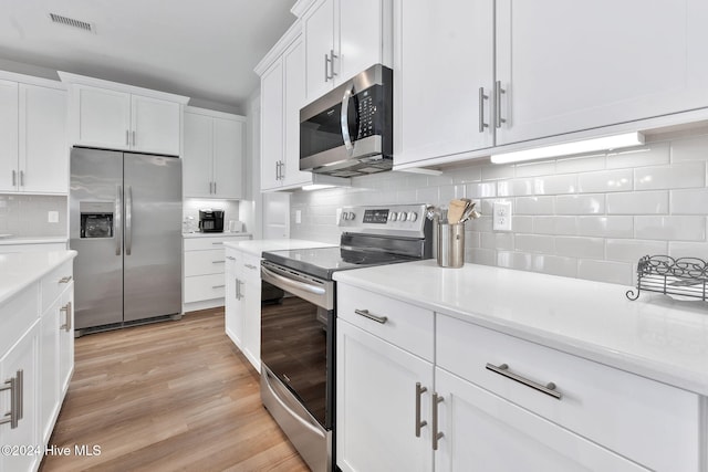 kitchen with decorative backsplash, light hardwood / wood-style flooring, white cabinets, and stainless steel appliances