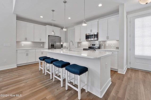 kitchen featuring white cabinets, sink, an island with sink, light hardwood / wood-style floors, and stainless steel appliances