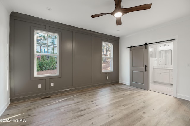 entryway featuring ceiling fan, light hardwood / wood-style flooring, and a barn door