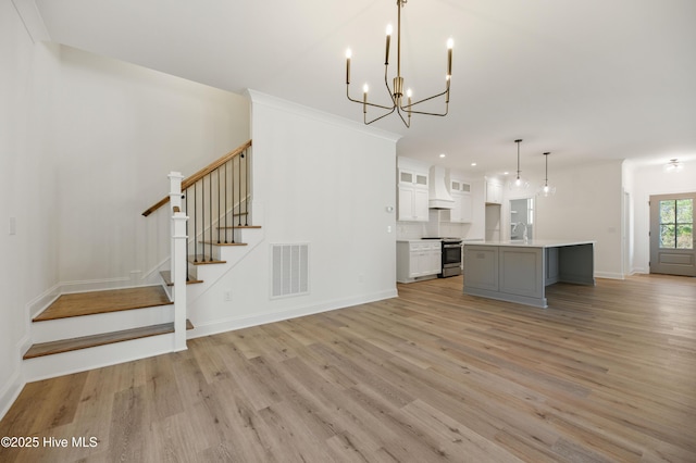 interior space with light hardwood / wood-style floors, sink, crown molding, and a notable chandelier