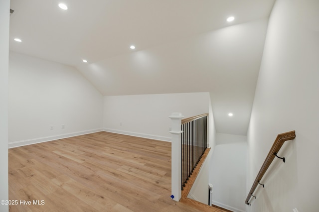 additional living space with light hardwood / wood-style floors and lofted ceiling