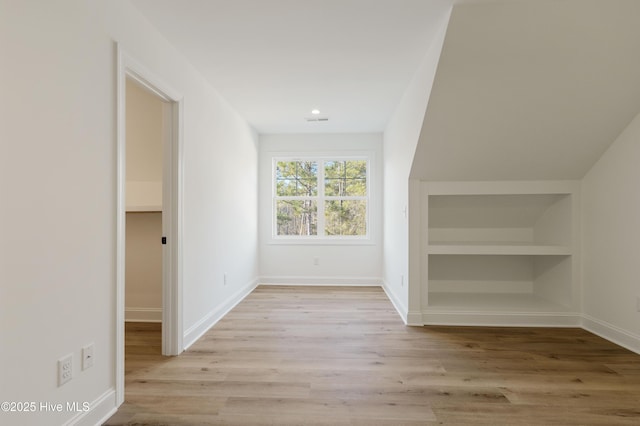 bonus room featuring built in features and light hardwood / wood-style flooring