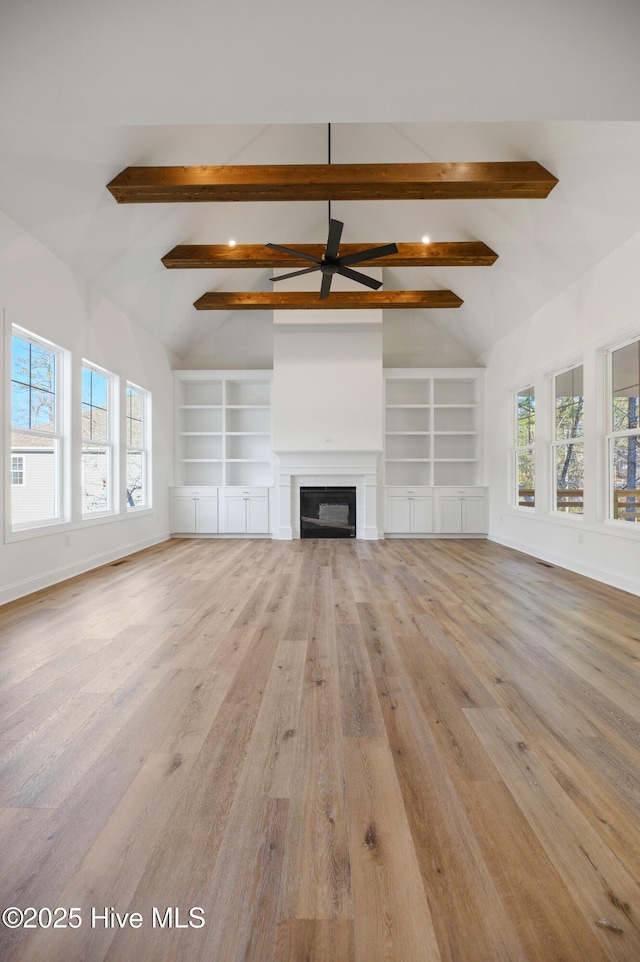 unfurnished living room with built in features, lofted ceiling with beams, and light wood-type flooring