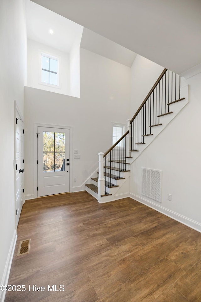 entrance foyer featuring hardwood / wood-style flooring and a towering ceiling