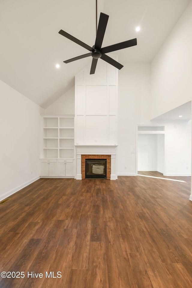 unfurnished living room featuring ceiling fan, dark hardwood / wood-style flooring, a fireplace, and high vaulted ceiling