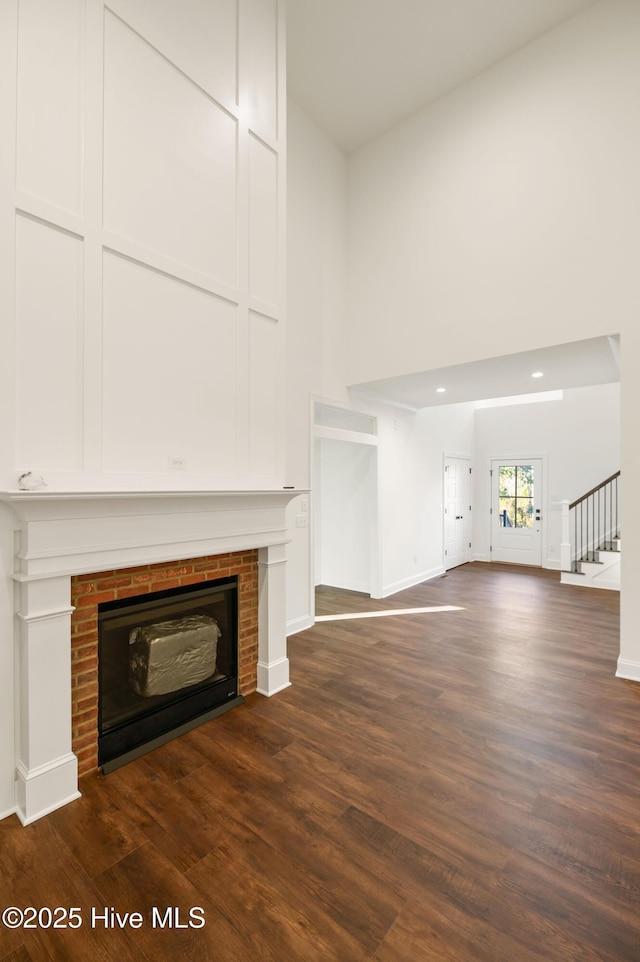 unfurnished living room with dark wood-type flooring and a brick fireplace