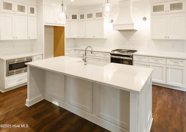 kitchen with premium range hood, appliances with stainless steel finishes, white cabinetry, and hanging light fixtures