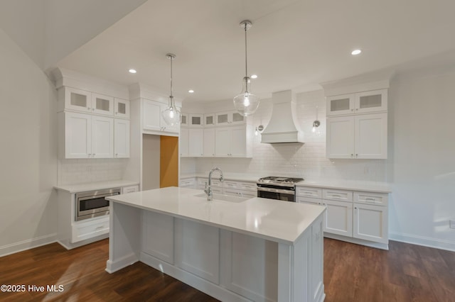 kitchen with premium range hood, appliances with stainless steel finishes, white cabinetry, and sink