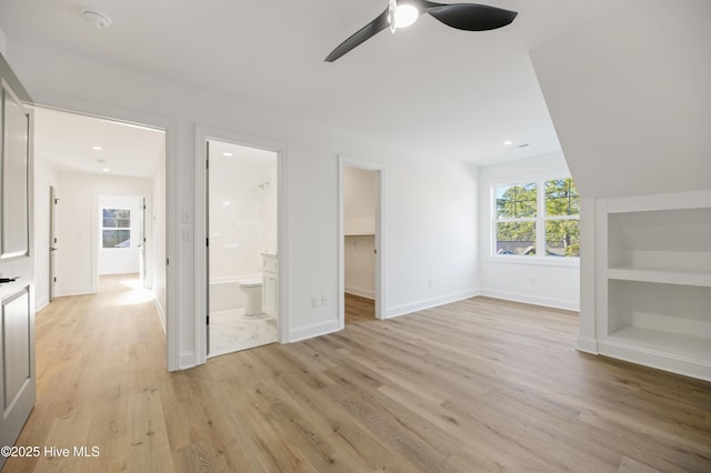 interior space with ceiling fan, light hardwood / wood-style flooring, a spacious closet, connected bathroom, and a closet