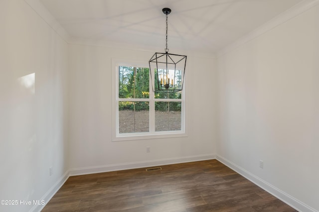 unfurnished dining area with dark hardwood / wood-style flooring, ornamental molding, and an inviting chandelier