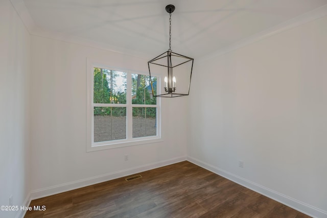 unfurnished dining area with dark hardwood / wood-style floors, crown molding, and a chandelier