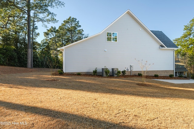 view of side of property with central AC unit and a yard