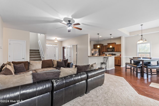 living room with ceiling fan with notable chandelier and dark hardwood / wood-style floors