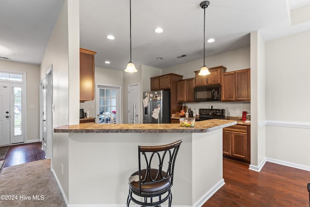 kitchen with decorative light fixtures, a kitchen bar, kitchen peninsula, and black appliances