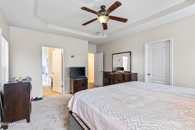 carpeted bedroom featuring ceiling fan and a tray ceiling