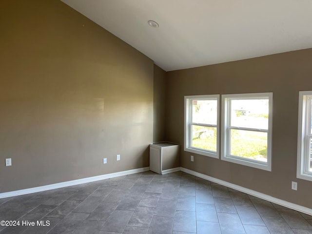 tiled empty room with lofted ceiling