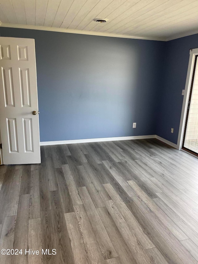 spare room featuring wood-type flooring, ornamental molding, and wooden ceiling