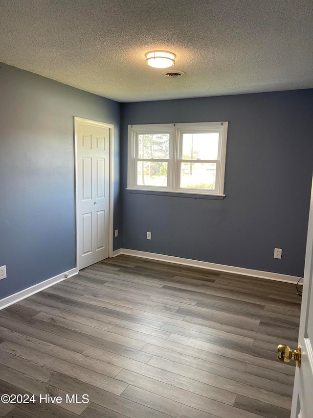 spare room featuring hardwood / wood-style floors and a textured ceiling