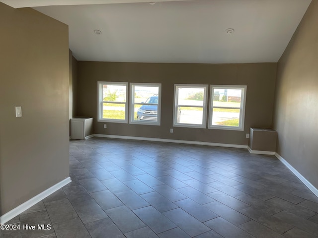 tiled empty room with lofted ceiling and a wealth of natural light