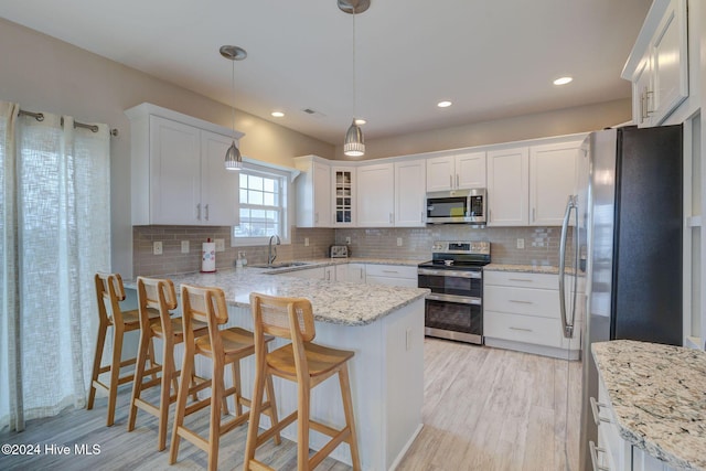 132 Reeves St, North Topsail Beach, NC 28460 - kitchen featuring stainless steel appliances, white cabinets, a breakfast bar area, decorative backsplash, and recessed lighting