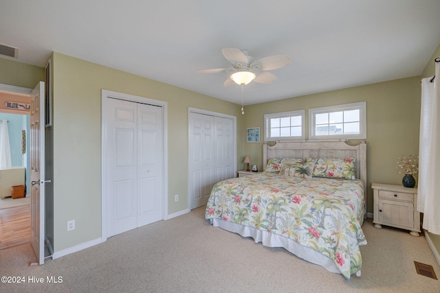 carpeted bedroom featuring ceiling fan and multiple closets