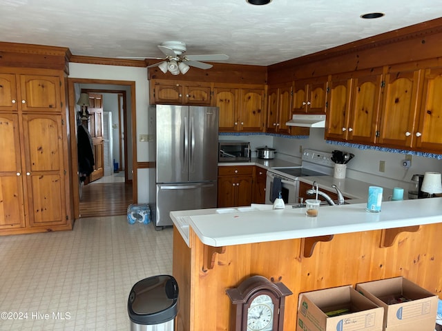 kitchen with a kitchen breakfast bar, ceiling fan, kitchen peninsula, and appliances with stainless steel finishes