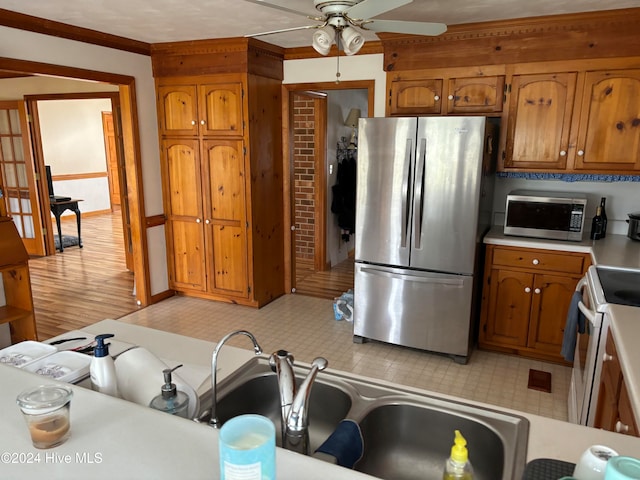 kitchen with ornamental molding, stainless steel appliances, ceiling fan, and light hardwood / wood-style floors