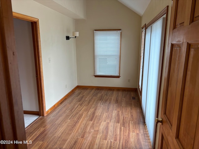 spare room featuring dark wood-type flooring and lofted ceiling