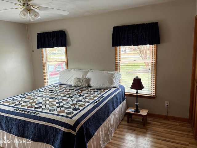 bedroom featuring hardwood / wood-style flooring, ceiling fan, and multiple windows