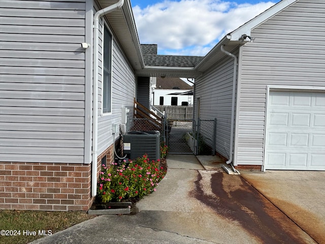 view of side of home with a garage and central air condition unit