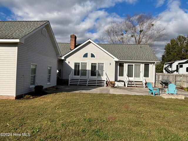 rear view of property featuring a lawn, a fire pit, and a patio area